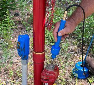 A hand holding a blue wand against a red hydrant.