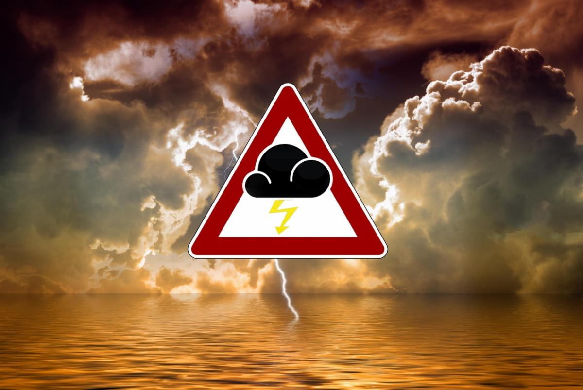 AI generated image of a large body of water with dark menacing clouds above; red warning triangle with a storm cloud and lightning superimposed in front.