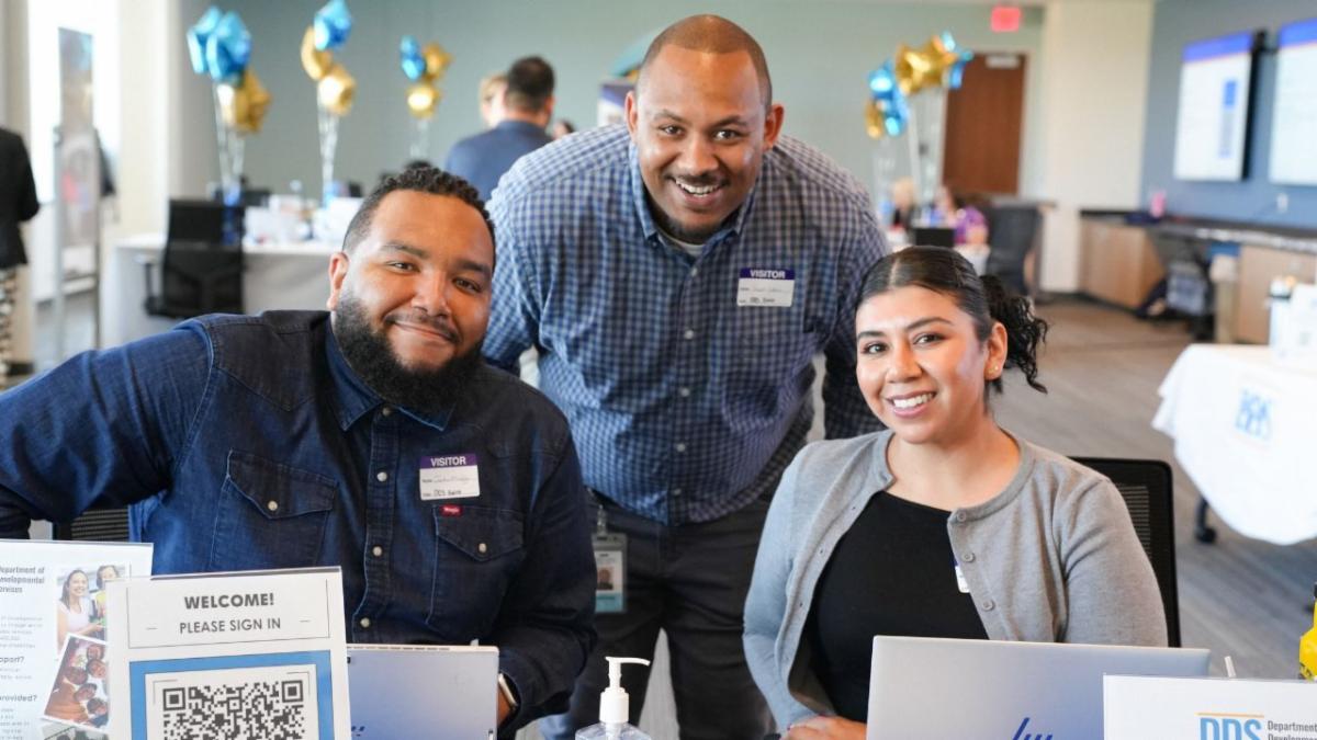 Three DDS employees smile at the camera at an ACRC hiring workshop