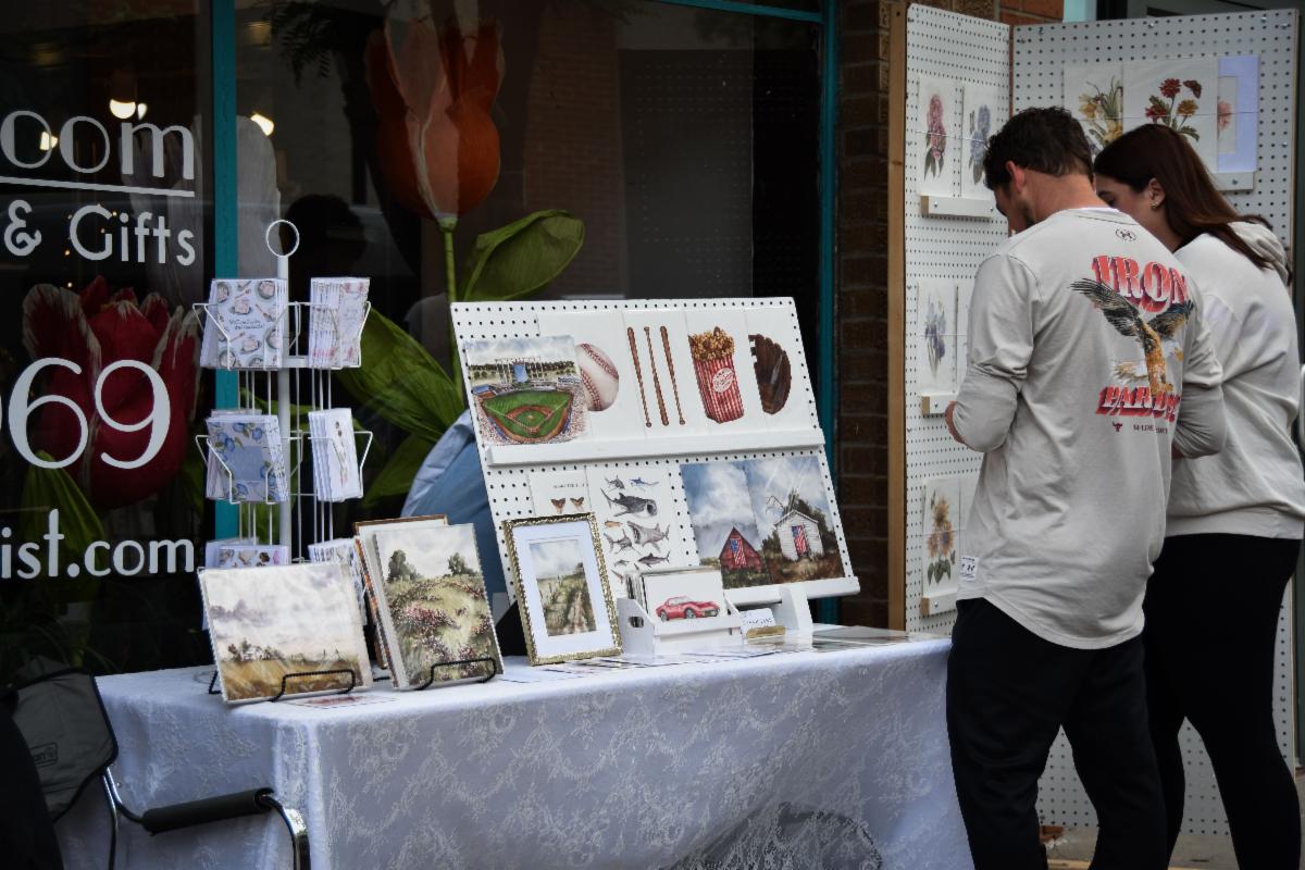 Man and woman stopped at a booth looking at art pieces