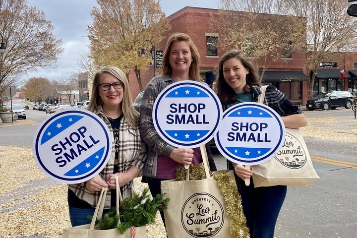 Image of three women holding small circular signs that say shop small
