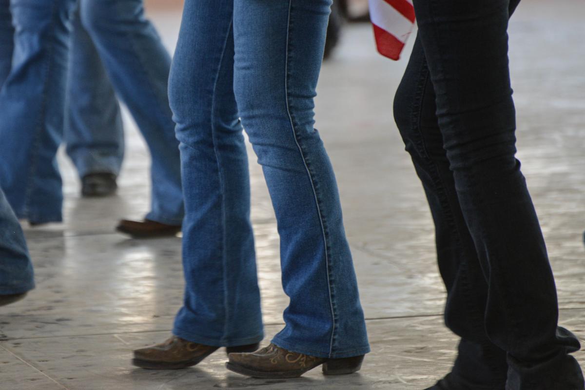 Group of people wearing jeans and cowboy boots line dancing