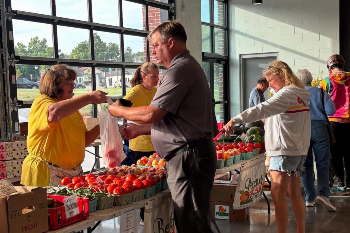 buying tomatos at a farmers market booth
