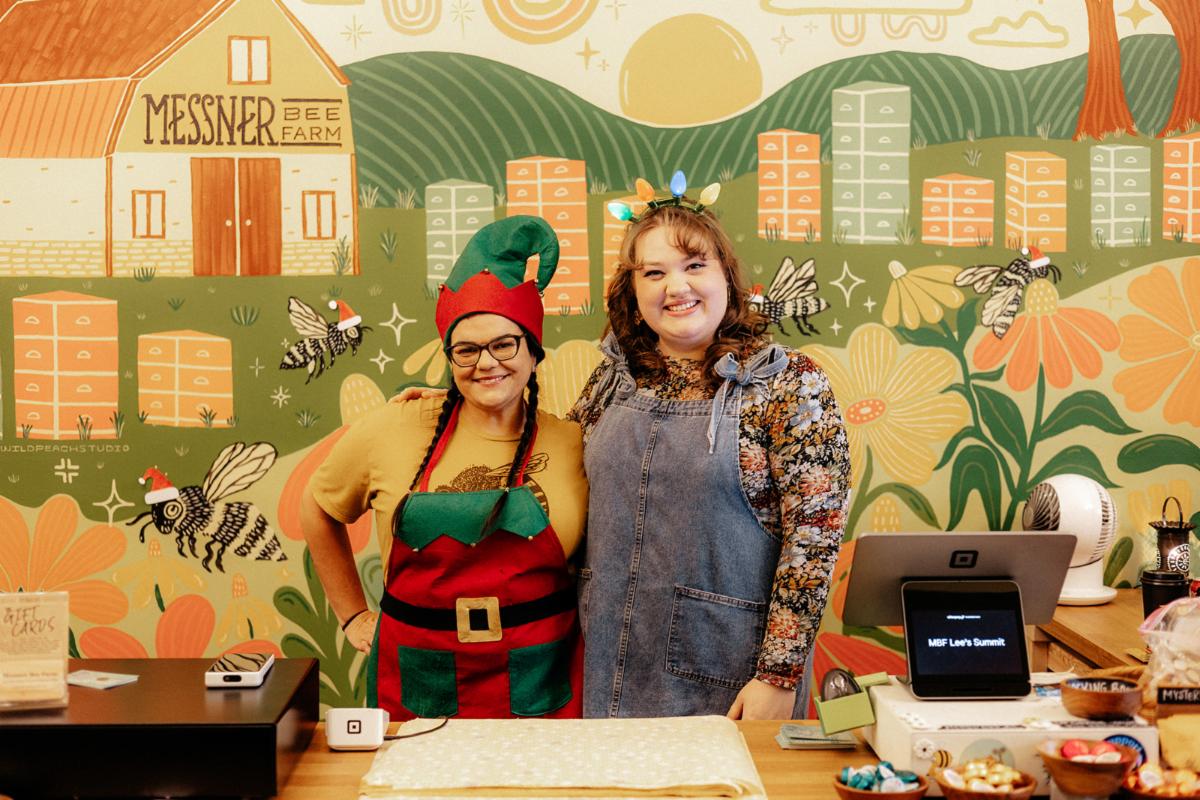Image of two women standing behind a cash register dressed in christmas outfits 
