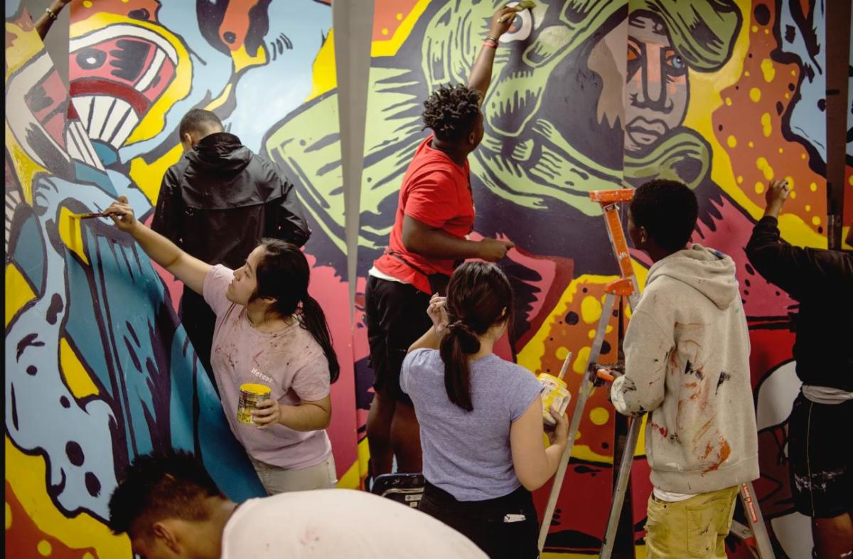 Photo of a group of people working on a collaborative mural. Urban ArtWorks is one of the Organization Award honorees at the 2023 Governor’s Arts & Heritage Awards. Photo courtesy of Urban ArtWorks.