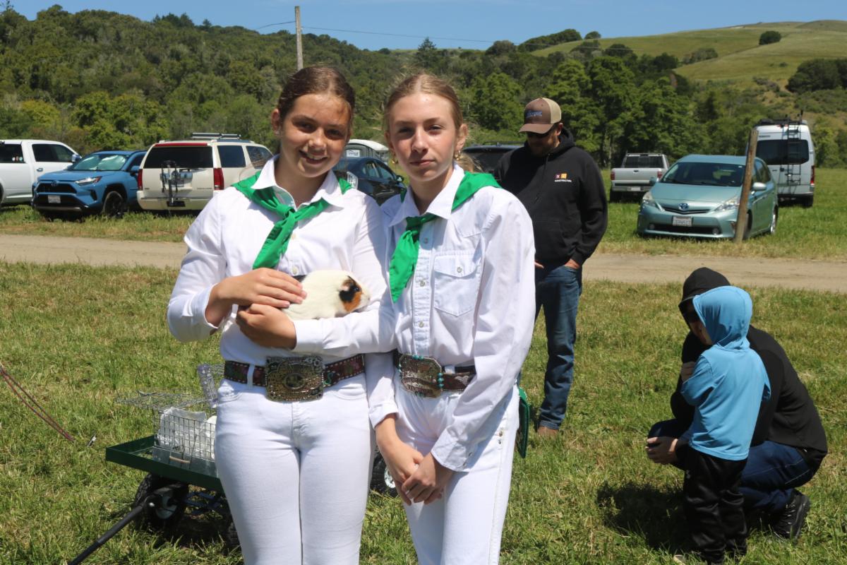 two youth members with a bunny wearing white and 4-H green uniforms