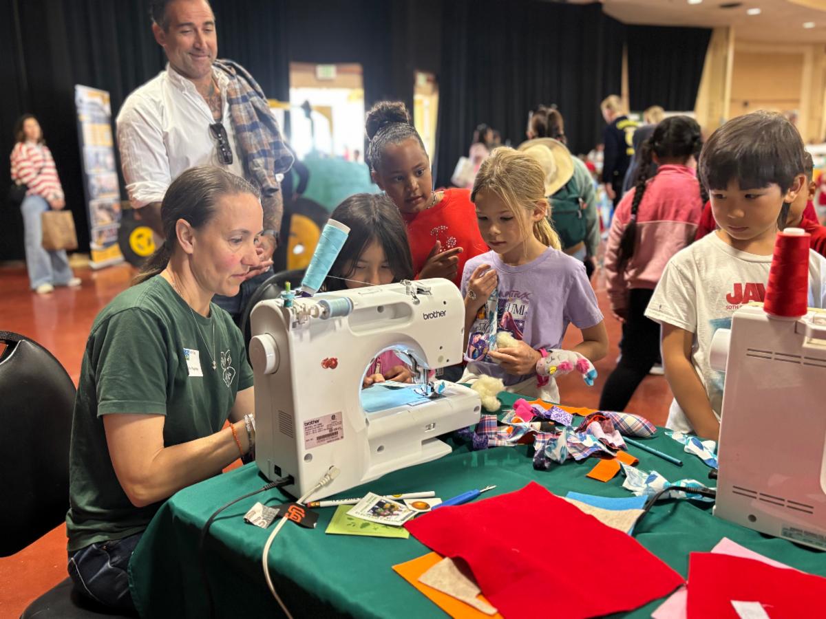 4-H Volunteer teaching students at the Farm Day event how to sew a basic stich with a sewing machine