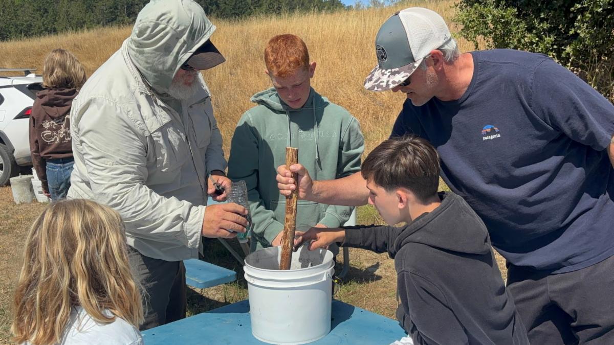 a chaperone, guest speaker and campers learning about water filtration at 4-H camp