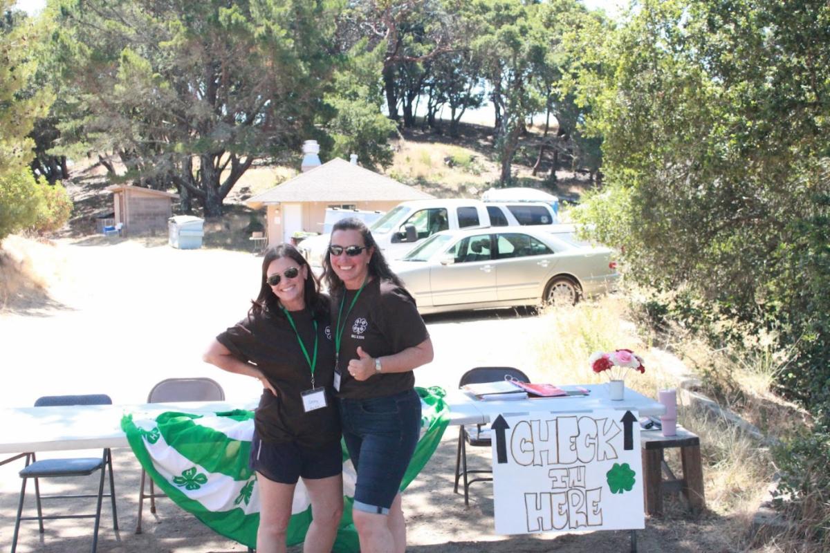 4-H camp chaperones at check in waiting for campers to arrive with smiles and good vibes