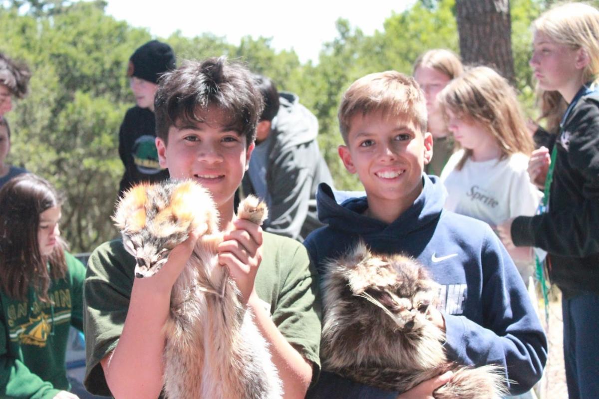 Campers holding up animal pelts at 4-H camp during a guest speaker presentation