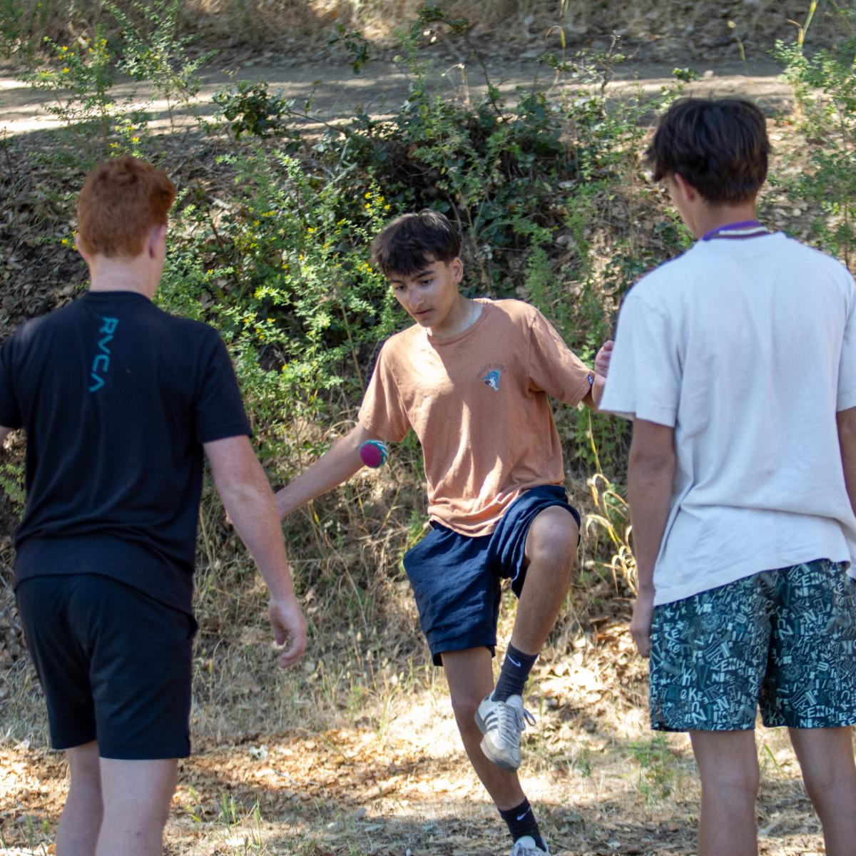 a group of 3 boys playing hacky sack