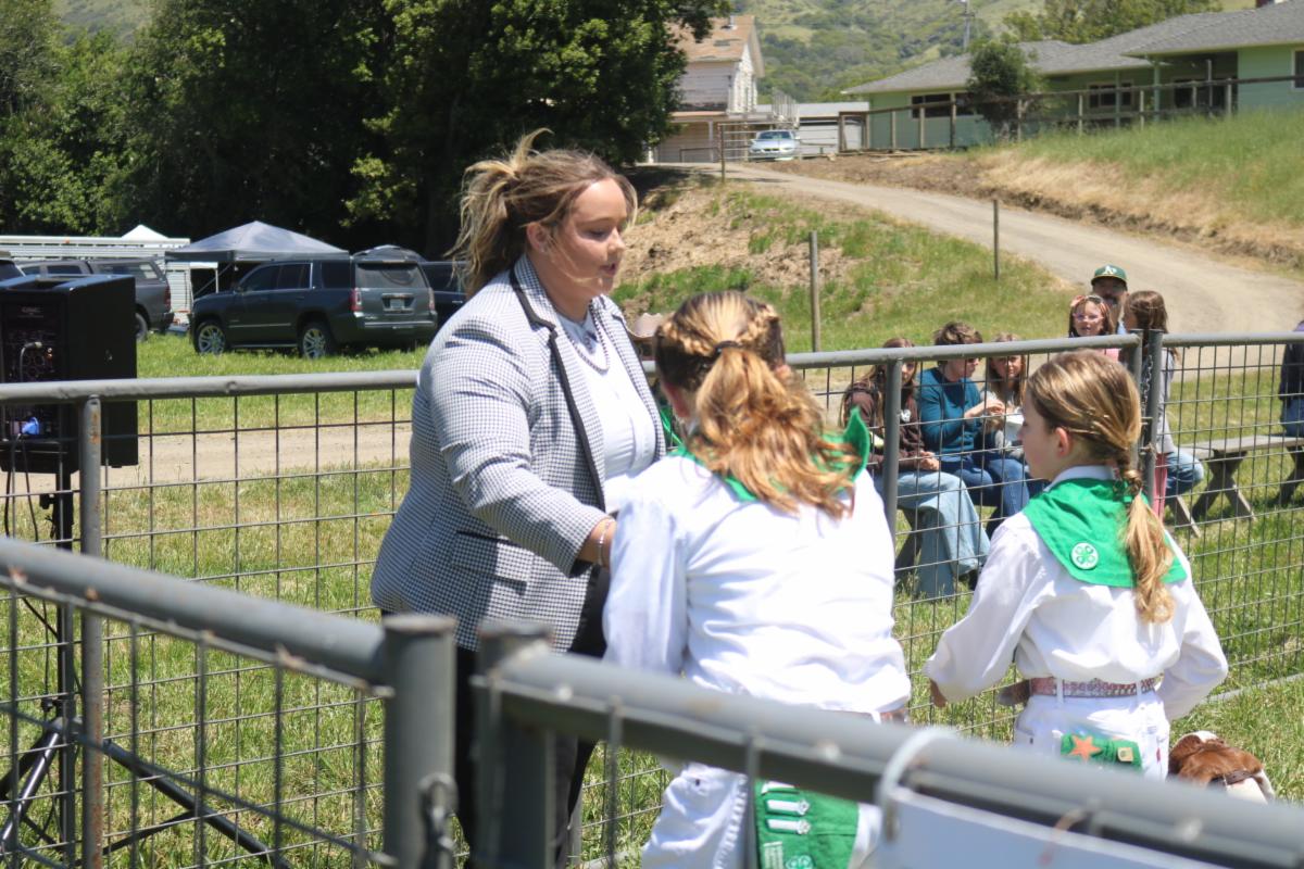 a woman talking to two youth members with their goats 