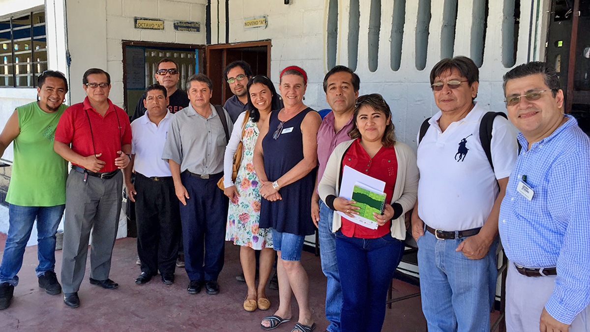Group of educators pose together outside a school building smiling during a professional visit