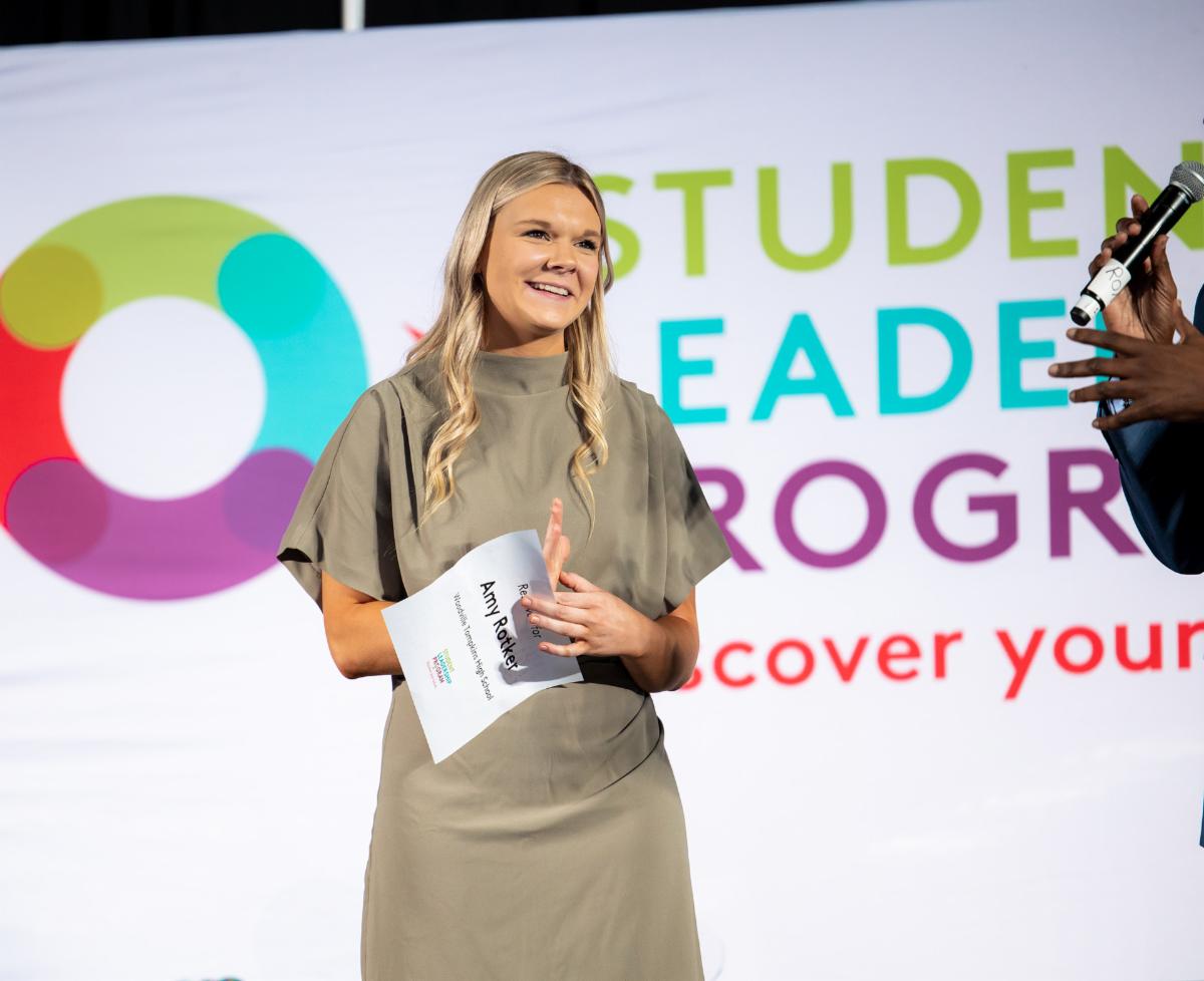 Photo of woman on stage in front of a large logo