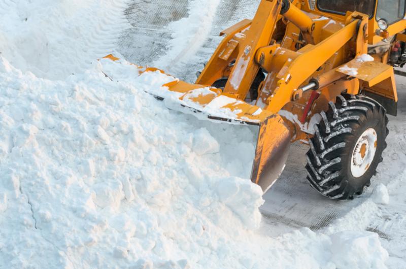 Stock photo of a backhoe removing a pile of snow.