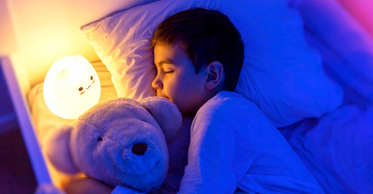 boy sleeping next to led night light