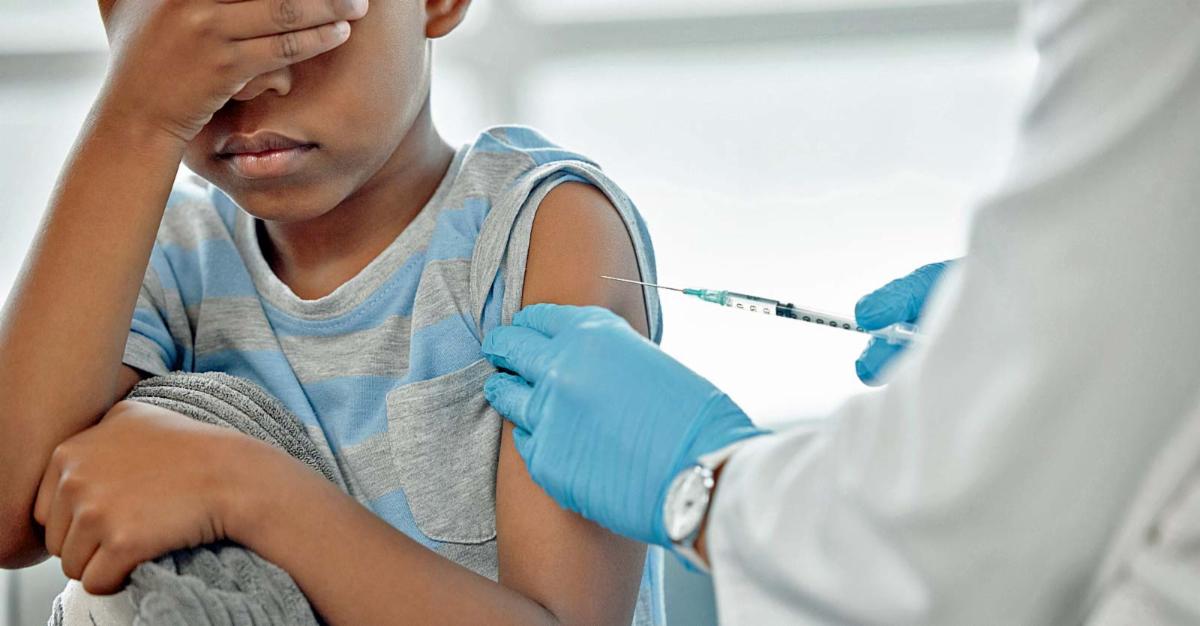 child getting vaccine covering eyes