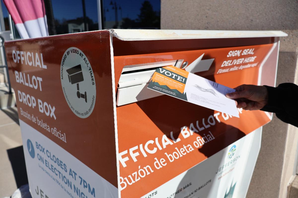 Voter depositing a completed ballot into an official election ballot drop box.
