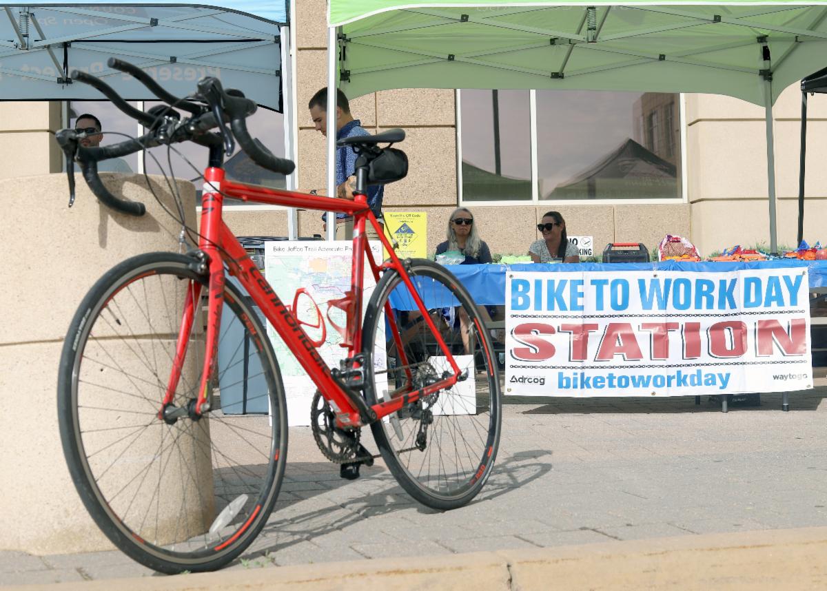 Red road bike parked beside a Bike to Work Day station tent.