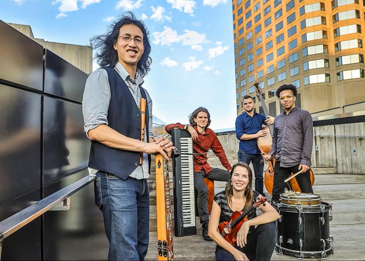 Musicians posing with instruments on a rooftop.