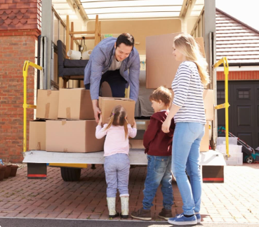 Family loading moving boxes into a truck together.