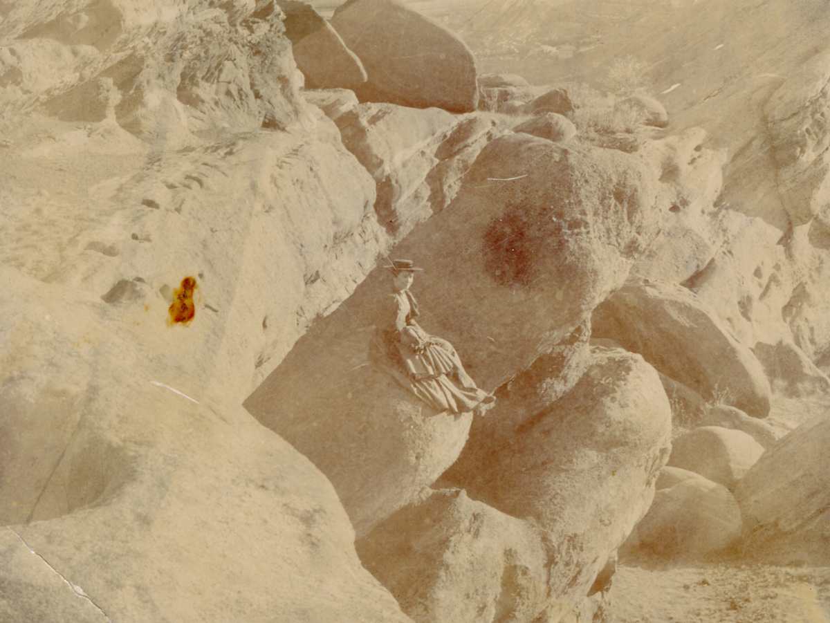 Unidentified woman in fancy dress sitting on a rock in Red Rocks Park.