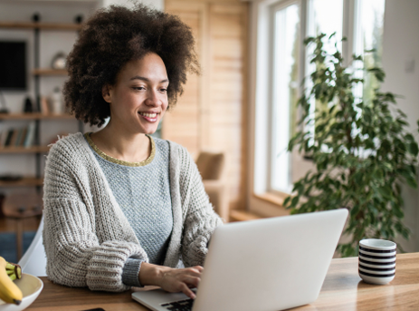 A woman smiles while working on a laptop.