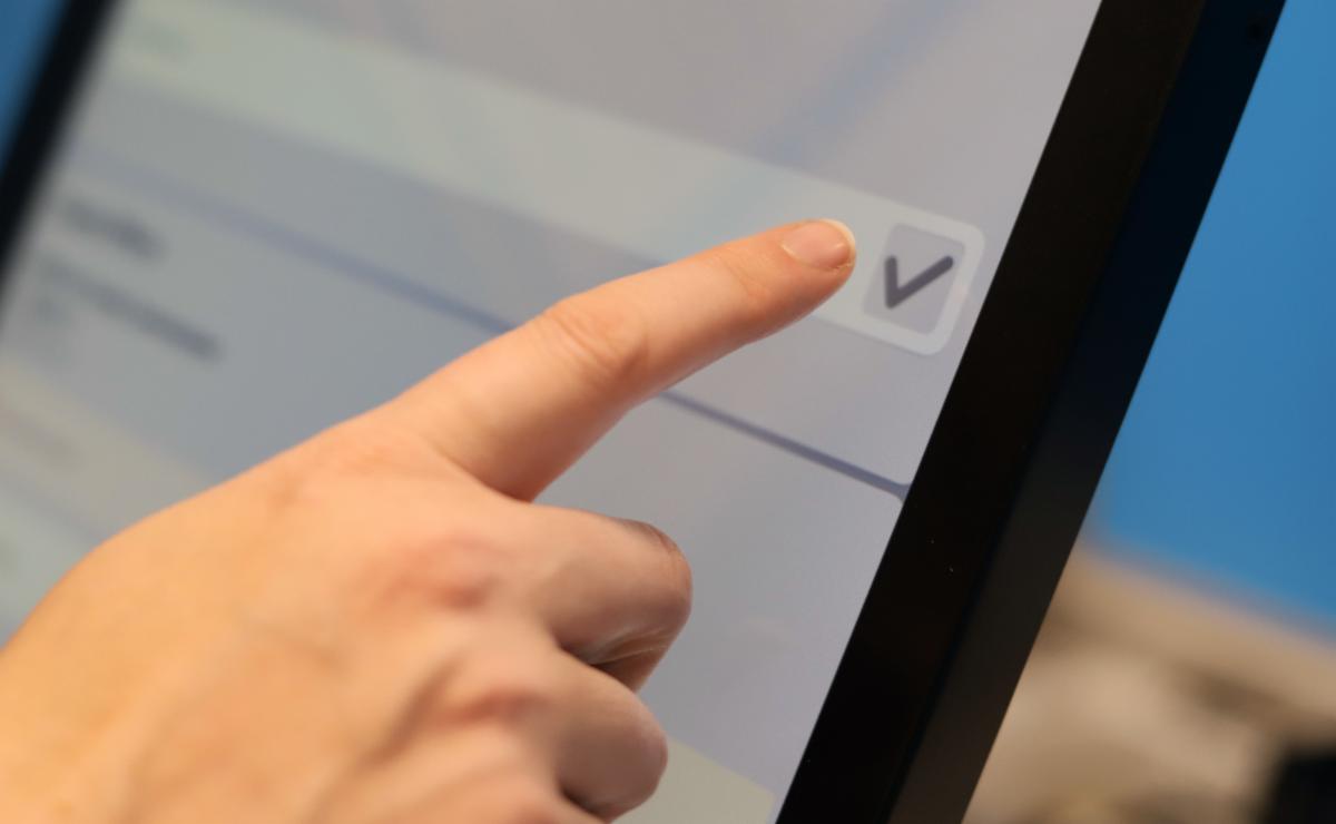 Voter selecting an option on an electronic voting touchscreen.