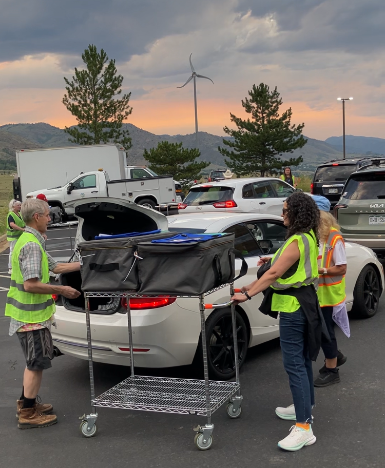 Election volunteers in safety vests assist drivers.