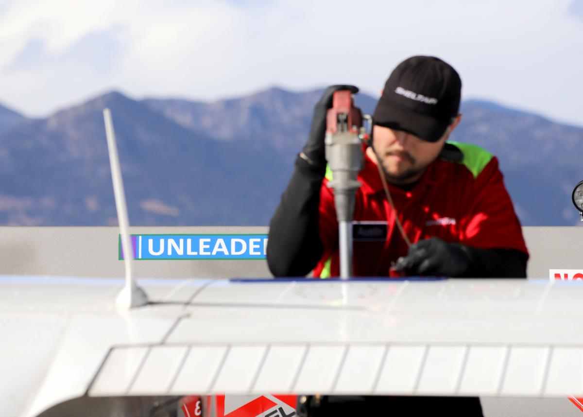 An airport staffer pumps fuel into a small plane from an unleaded gas tanker.
