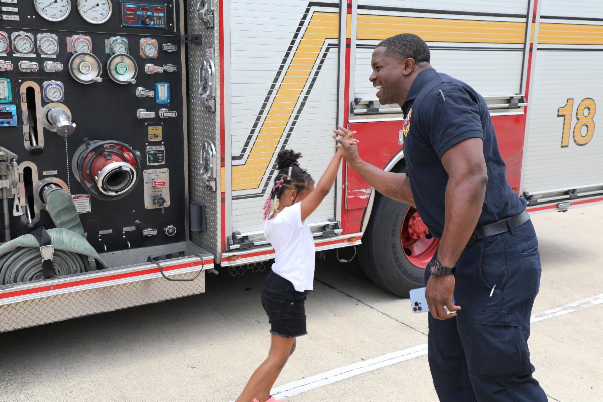 Austin public safety professional high-fiving a young child near a fire truck