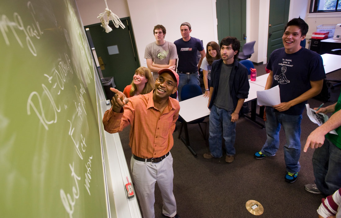 Image of someone pointing to a blackboard in a classroom