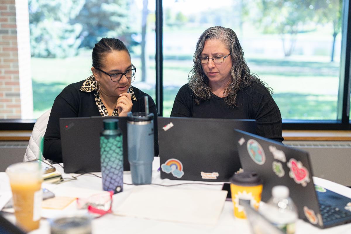 Two people working together on laptops at a table.