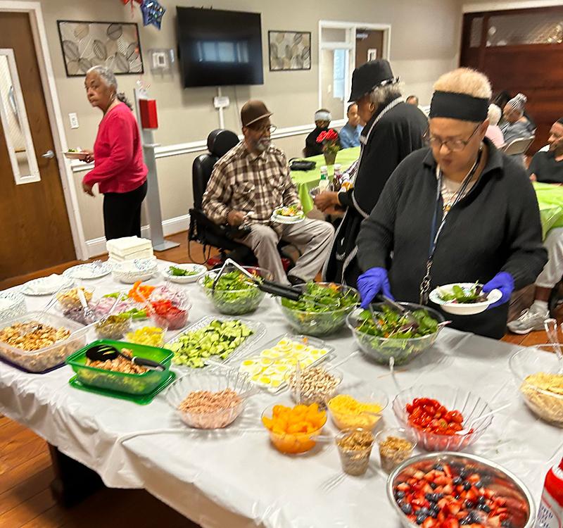 woman making a plate from a buffet table with other people in the background