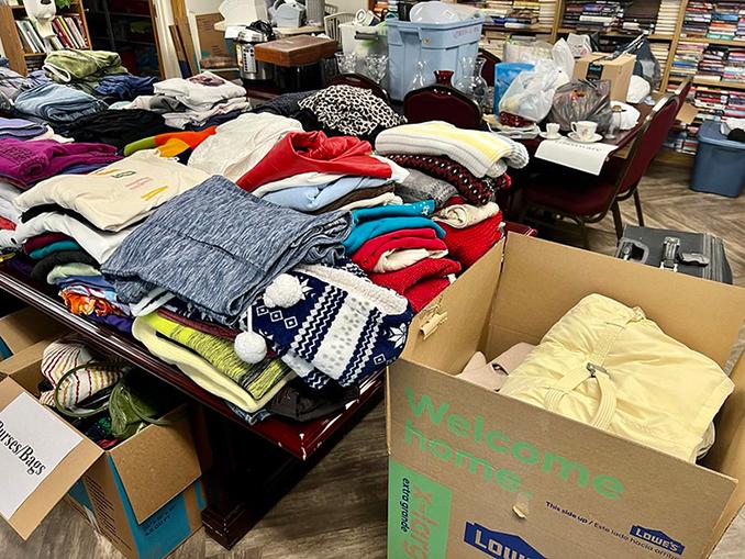 large piles of clothing displayed on tables and in a box