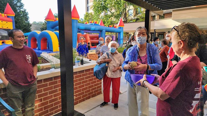 residents and staff outside with carnival activities and a bounce house in the background