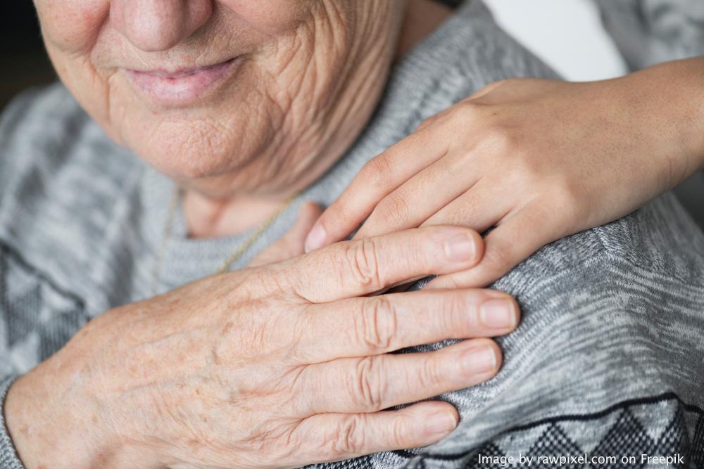 close up of young hand on the shoulder of an older lady