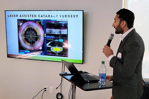 man standing in front of a screen showing a powerpoint presentationand holding a mic while giving a presentation on glaucoma 