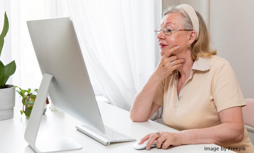 woman looking at a computer monitor with one hand on her chin and the other on a mouse