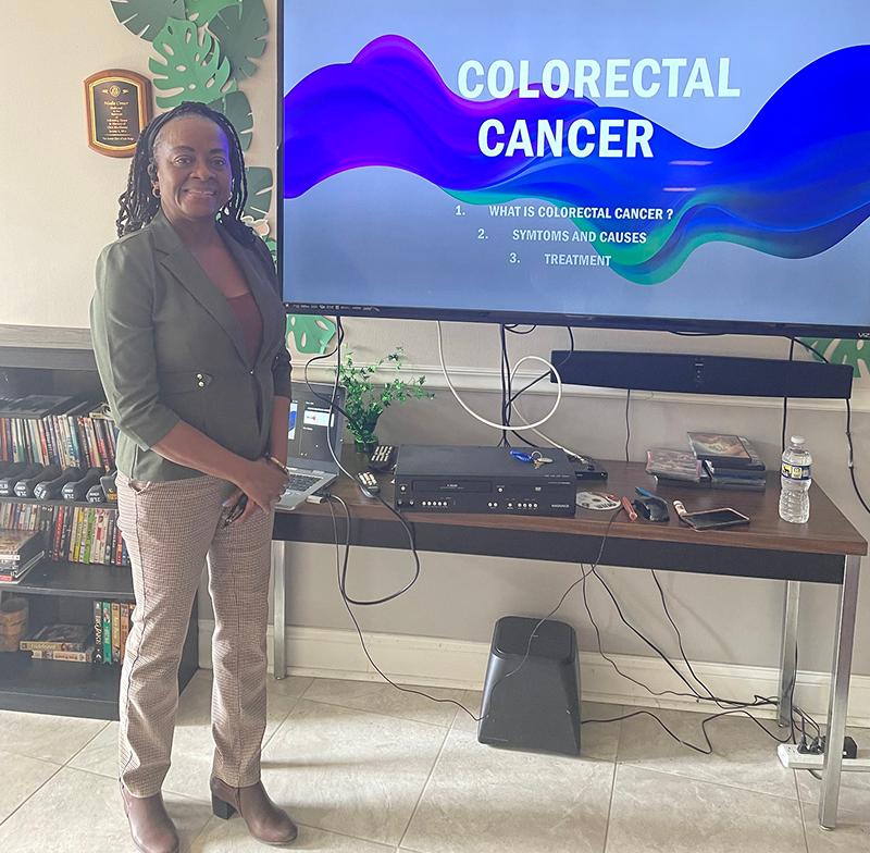 Woman standing in front of a screen that says Colorectal Cancer