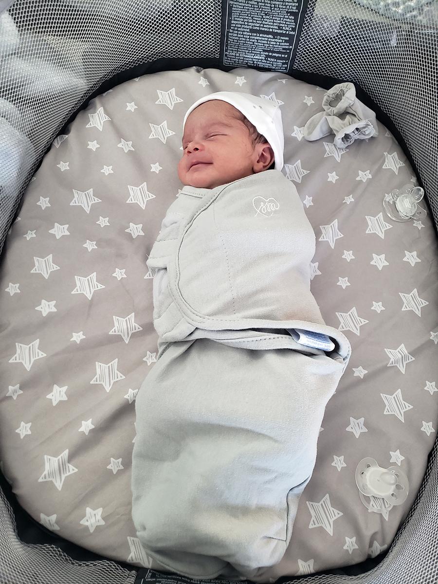 small baby wrapped in grey swaddling and a small hat