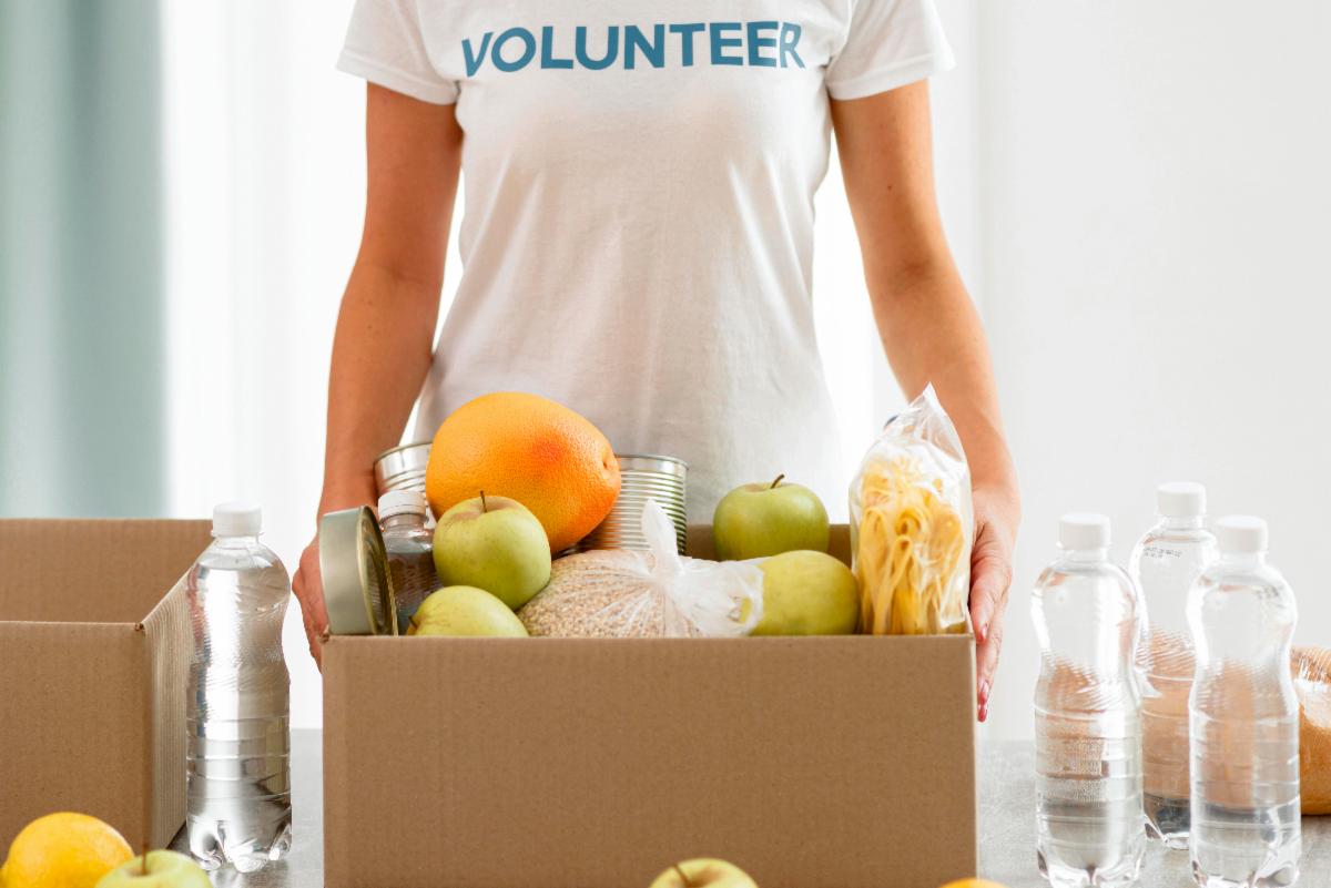 person in white tshirt standing behind a box of food