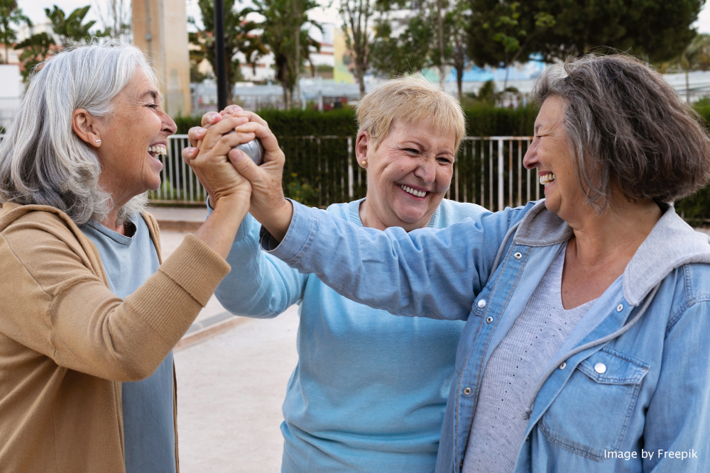 Three older ladies clasping hands