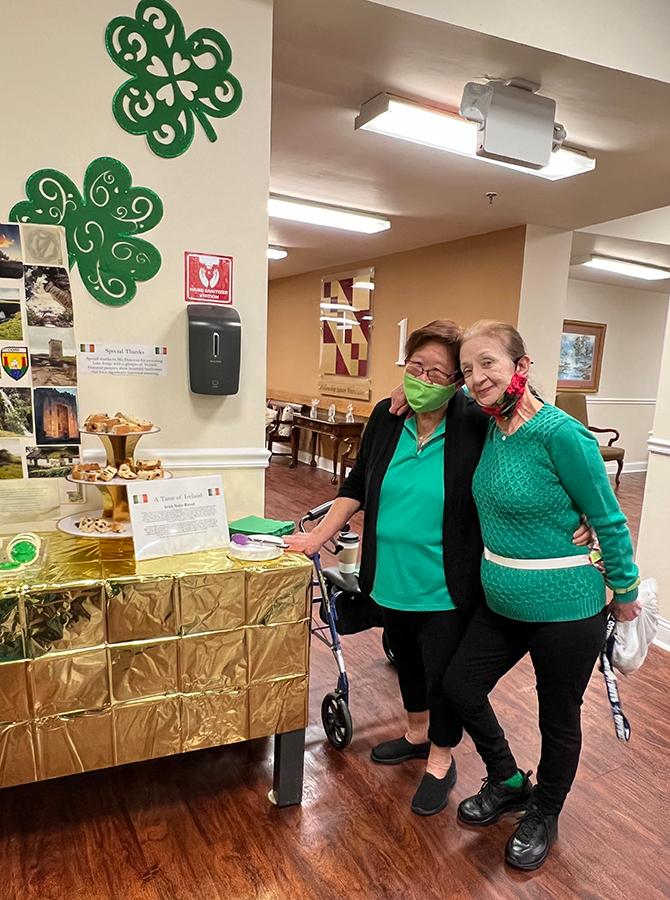 two women dressed in green pose by Saint Patricks day decorations