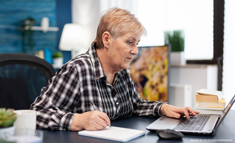 mature-woman-taking-notes-notebook-working-home-office