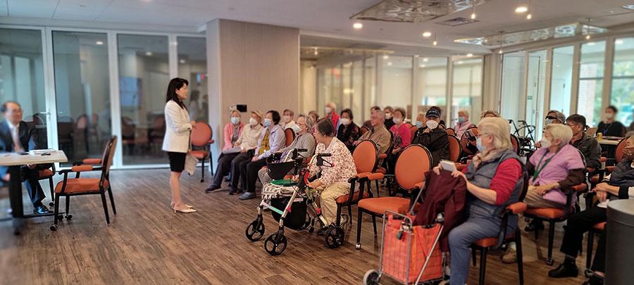 roomful of residents listening to a standing woman giving a presentation while a man sits at a table