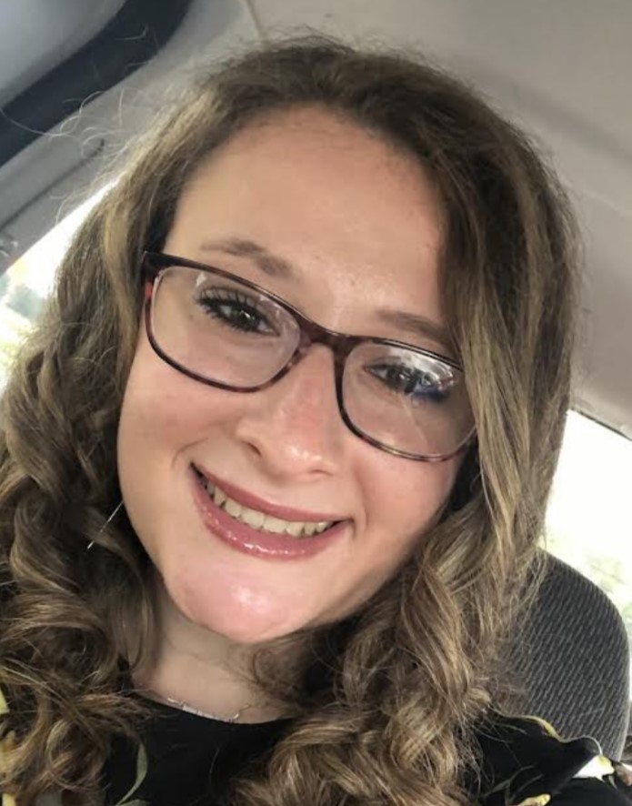Carly headshot young woman with glasses and long curly hair