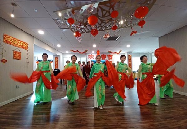 group of ladies dressed in green and red clothing for lunar new year performing a dance