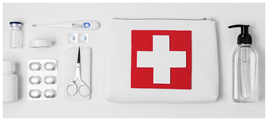 first aid kit and supplies laid out on white background