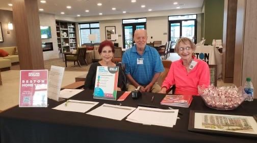 Two women and one man seated behind an information table